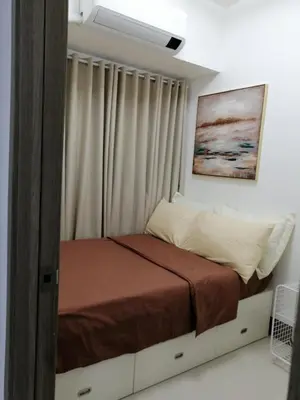 a bed in a bedroom with a window with avertisementatronatron at Vistaro Stays at Fame Residences in Manila