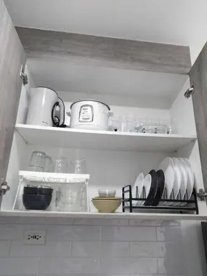 a kitchen shelf with dishes and utensils on it at Vistaro Stays at Fame Residences in Manila