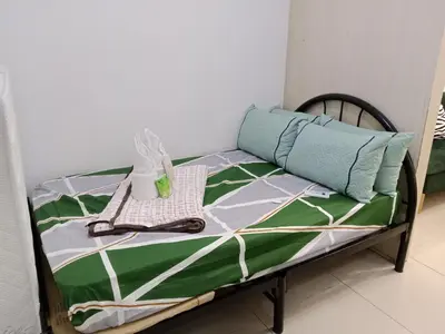 a bed with a green and white quilt on it at Sea Residence Tower A by Stave in Manila
