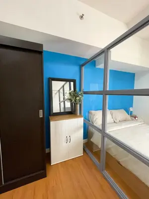 a bedroom with blue walls and a bed and a mirror at 1 BR Condo in Manila near US Embassy & St Lukes in Manila