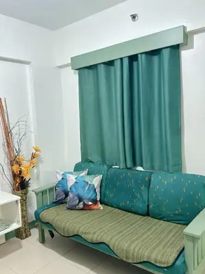 a green couch in a living room with a green curtain at Apartment in Parañaque in Manila