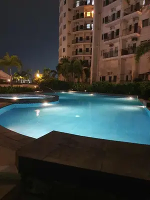 a large blue swimming pool at night with buildings at Circulo verde in Manila