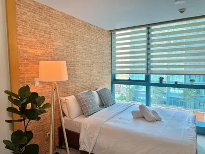 a bedroom with a bed and a large window at Chic 1-BR at Uptown BGC in Manila