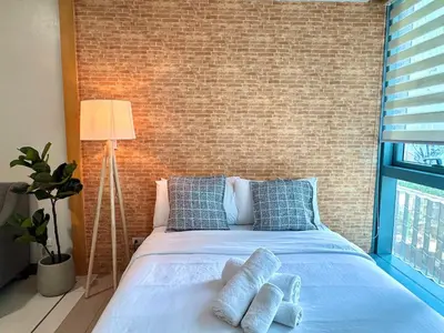 a bedroom with a bed with blue pillows and a brick wall at Chic 1-BR at Uptown BGC in Manila