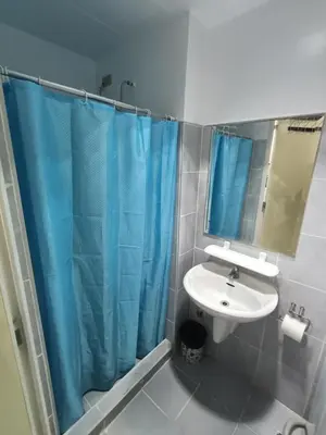 a bathroom with a sink and a blue shower curtain at Derick's Place at Sea Residences in Manila