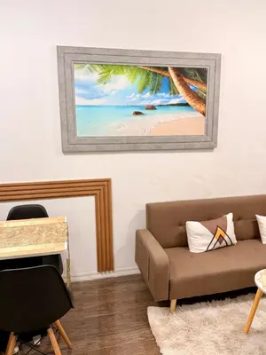a living room with a couch and a painting of a beach at Santa Cosy Villa suite-B Fast Wi-Fi, Netflix Included Split system Air-con & Hot Shower Close to Enchanted Kingdom in Santa Rosa