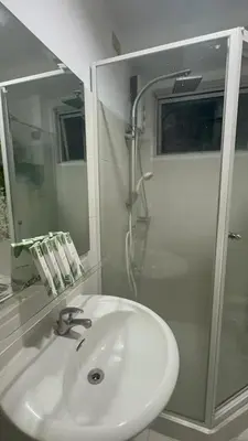 a white bathroom with a sink and a shower at A & M SUITE VACAY - Sea Residences Mall Of Asia Pasay in Manila