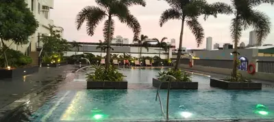 a swimming pool with palm trees in a building at Cozy Gutz Place at 16th in Manila