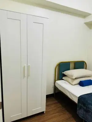 a bedroom with a white cabinet next to a bed at Vtan Condo in Manila
