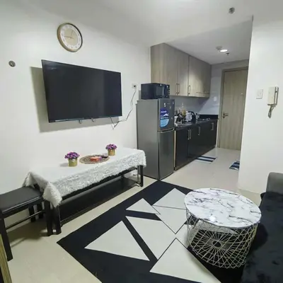 a living room with a table and a tv on the wall at Cityscape staycation in Manila