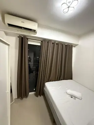 a bedroom with a white bed and a window at Cityscape staycation in Manila