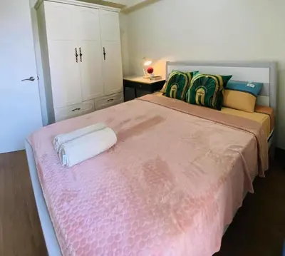 a bedroom with a large bed with a pink blanket at Stan Condo in Manila