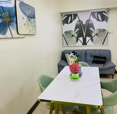 a white table with green chairs and a couch at Stan Condo in Manila