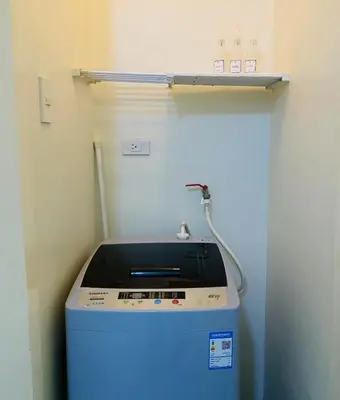 a washing machine in a room with a shelf at Stan Condo in Manila