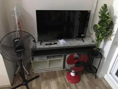 a living room with a television and two fans at Cosy Studio with balcony 100mbps and Netflix in Manila