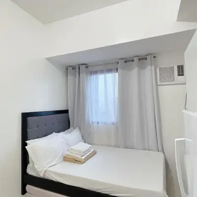 a bed in a room with a window at Studio Unit at Grand Riviera Suites in front of US Embassy in Manila