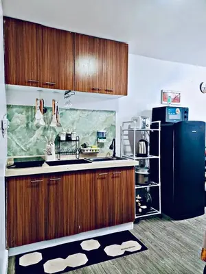 a kitchen with wooden cabinets and a black refrigerator at Cozy and comfy place at Ortigas Pasig City in Manila