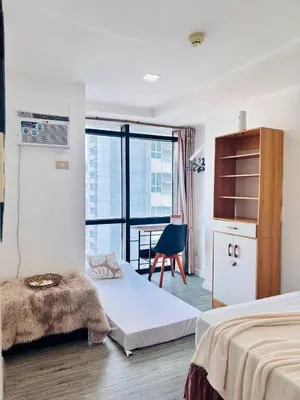 a hotel room with two beds and a chair at Cozy and comfy place at Ortigas Pasig City in Manila