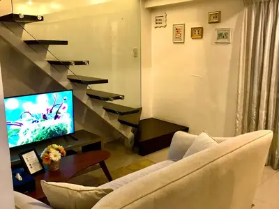 a living room with a couch and a flat screen tv at MaxStays - Max Home at Fort Victoria Tower A in Manila
