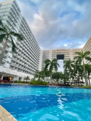 a large swimming pool in front of a large building at Cozy Place at Shell Residences in Manila