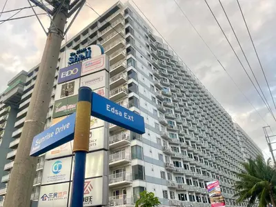 a street sign in front of a tall building at Cozy Place at Shell Residences in Manila