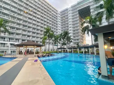 a swimming pool in front of a large building at Cozy Place at Shell Residences in Manila