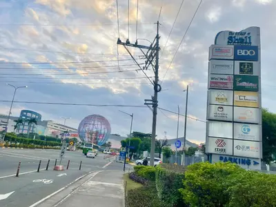 a sign for a gas station with a ferris wheel in the background at Cozy Place at Shell Residences in Manila