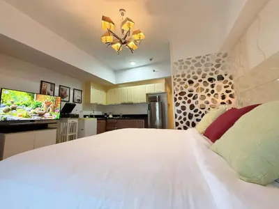 a bedroom with a large white bed and a kitchen at MaxStays - Max Home at The Venice Residences in Manila