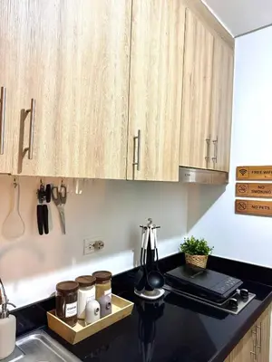 a kitchen with wooden cabinets and a black counter top at Philhaus Staycation 2025 in Manila