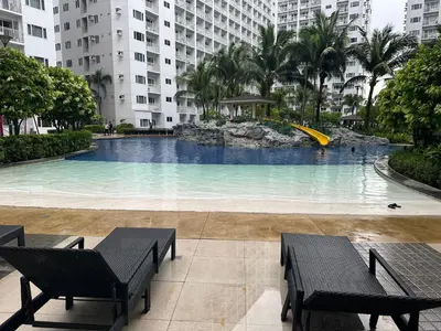 a large swimming pool in a city with two benches at marbys pad shore residences in Manila