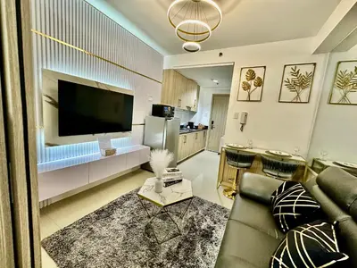 a living room with a couch and a large television at marbys pad shore residences in Manila