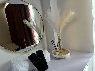 a table with a mirror and a vase with feathers at marbys pad shore residences in Manila