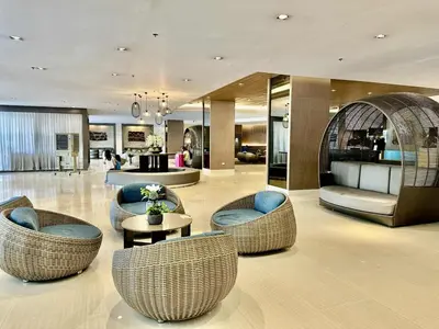 a lobby with chairs and tables in a building at staycation condo one bedroom balcony w pool view near SMX SM MOA IKEA NAIA DFA OCEAN PARK in Manila