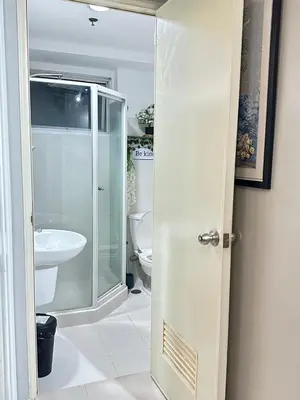 a bathroom with a glass shower and a toilet at Les Chambres Cosy - Sea Residences MOA PASAY in Manila