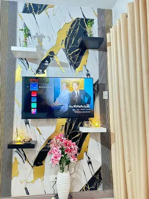 a wall with a tv and flowers in a vase at Les Chambres Cosy - Sea Residences MOA PASAY in Manila