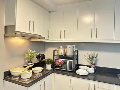 a kitchen with white cabinets and a microwave at Les Chambres Cosy - Sea Residences MOA PASAY in Manila