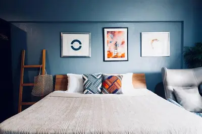 a bedroom with a blue wall with a bed with pillows at Functional stay near airport, business districts in Manila