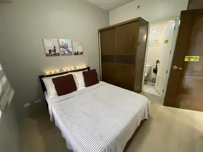 a bedroom with a bed with white sheets and brown pillows at Bekipay Suite at One Palm Tree right across NAIA 3 in Manila