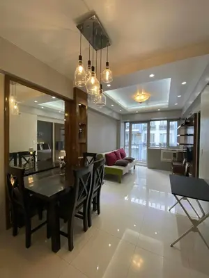 a dining room and living room with a table and chairs at Bekipay Suite at One Palm Tree right across NAIA 3 in Manila