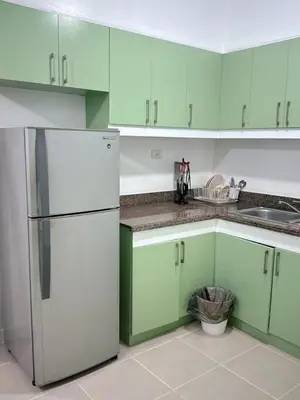 a kitchen with green cabinets and a white refrigerator at Stan Condo in Manila