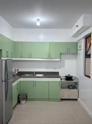 a green and white kitchen with green cabinets at Stan Condo in Manila