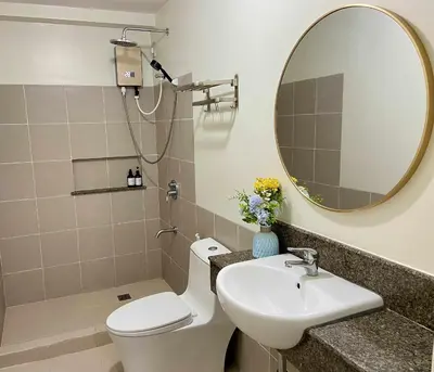 a bathroom with a sink and a toilet and a mirror at Vtan Condo in Manila