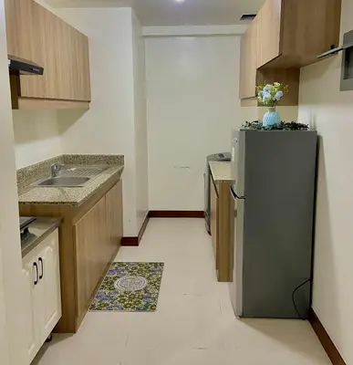 a small kitchen with a refrigerator and a sink at Vtan Condo in Manila