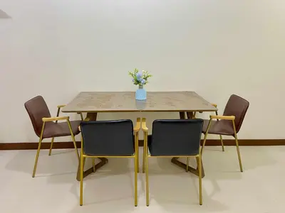 a table with chairs and a vase of flowers on it at Vtan Condo in Manila