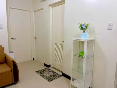 a room with a shelf with a vase of flowers on it at Vtan Condo in Manila