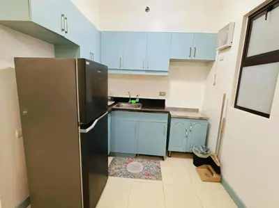 a small kitchen with blue cabinets and a refrigerator at Arista place staycation in Manila