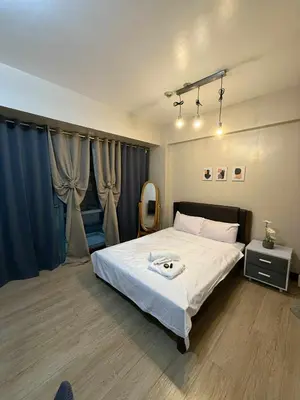 a bedroom with a large white bed with blue curtains at MCV Condotel Near Terminal 3 in Manila