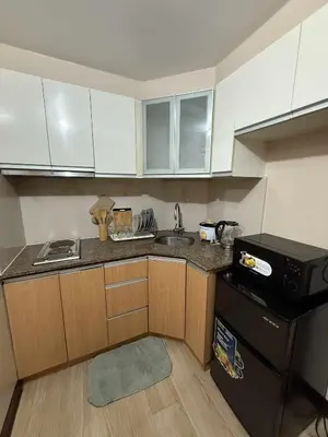 a small kitchen with white cabinets and a black refrigerator at MCV Condotel Near Terminal 3 in Manila