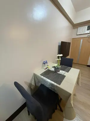 a dining room table with a blue chair and a white table and chairs at MCV Condotel Near Terminal 3 in Manila
