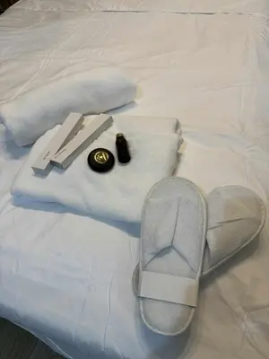 a pair of slippers and towels on a bed at MCV Condotel Near Terminal 3 in Manila